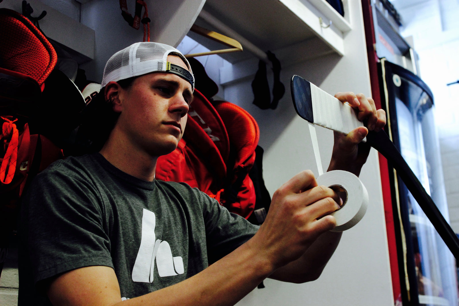 Player taping stick in locker room stall