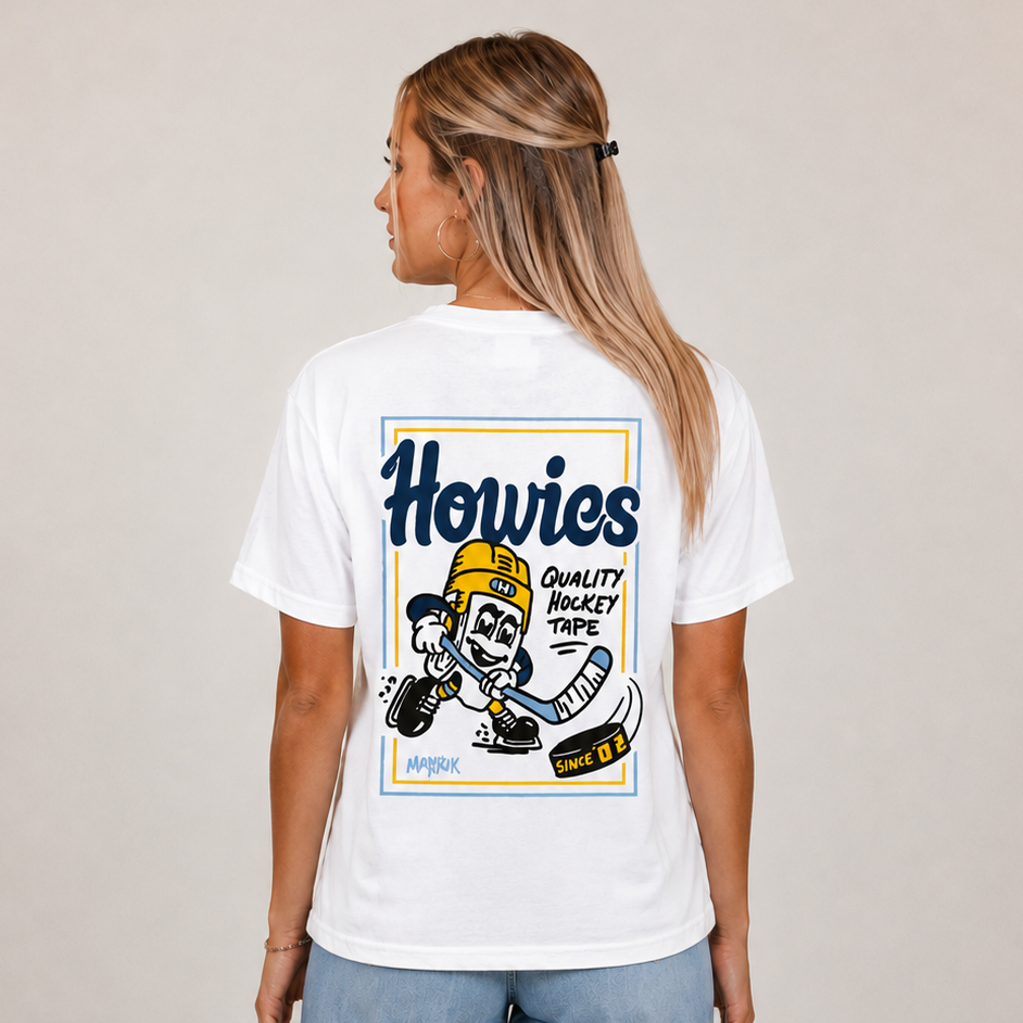 A woman shown from the back wearing a white graphic t-shirt with a large 'Howies' cartoon hockey graphic on the back, paired with light blue wide-leg jeans, against a neutral beige studio background.
