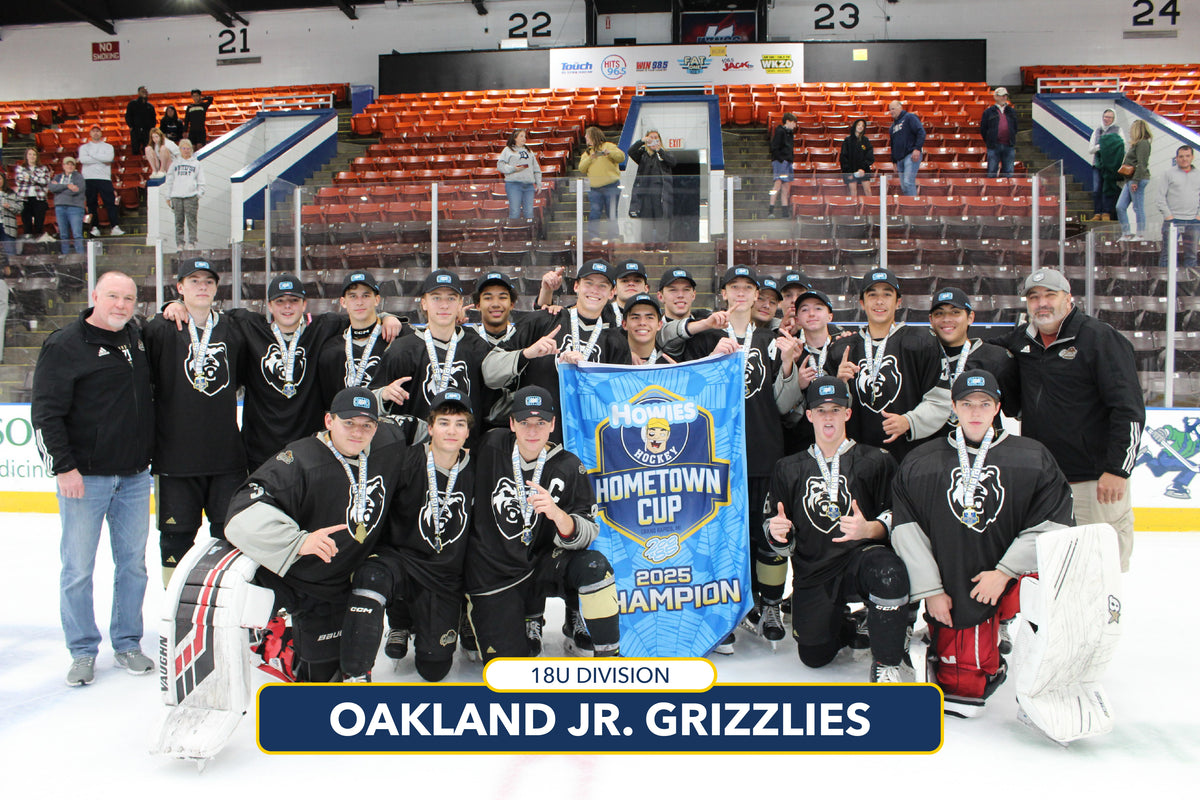 Hockey team posing with a banner on an ice rink, with 'Oakland Jr. Grizzlies' displayed.