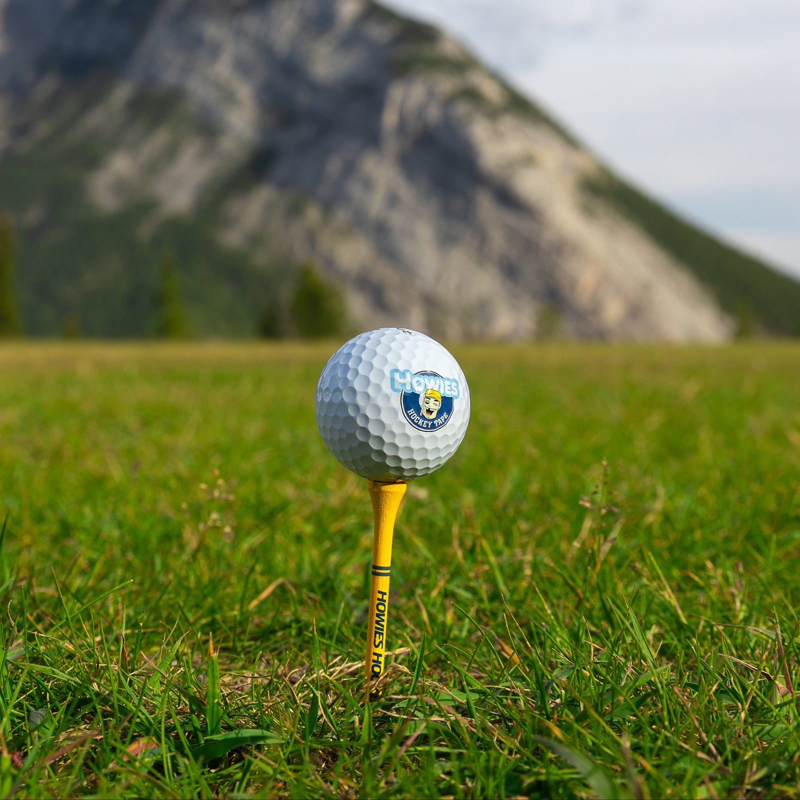 Golf ball on a tee with mountains in the background