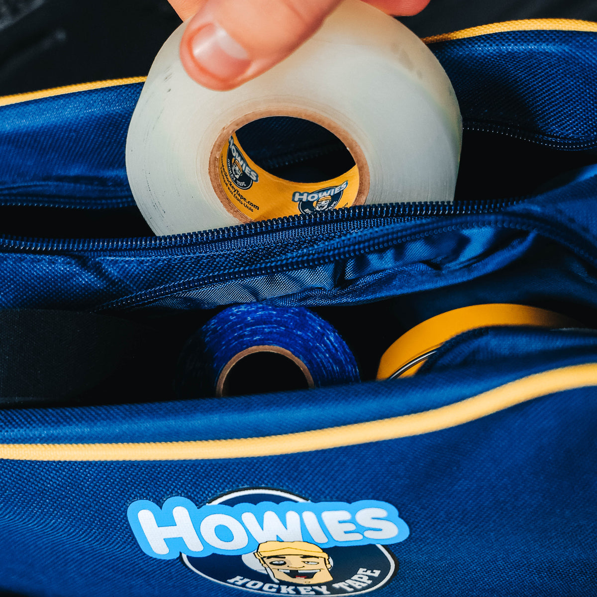 Person pulling a roll of clear tape out of  a howies accessory bag