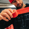 Person wearing a red beanie and black hoodie holding a red hockey stick