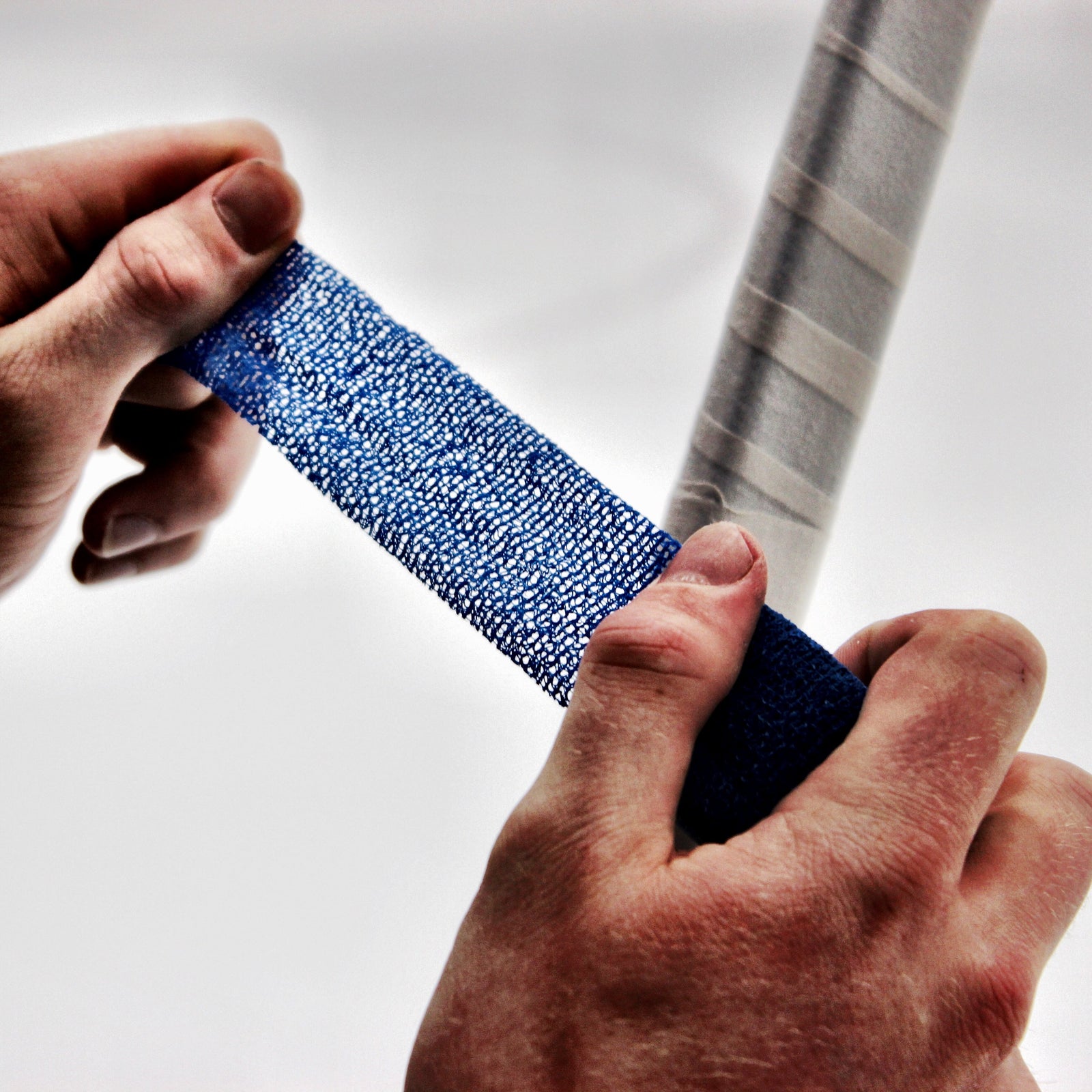 Person applying blue tape to a hockey stick knob