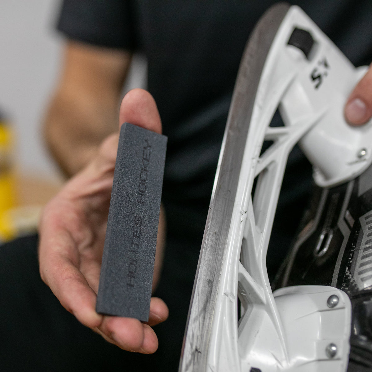 Person holding a white skate and a black hockey stone