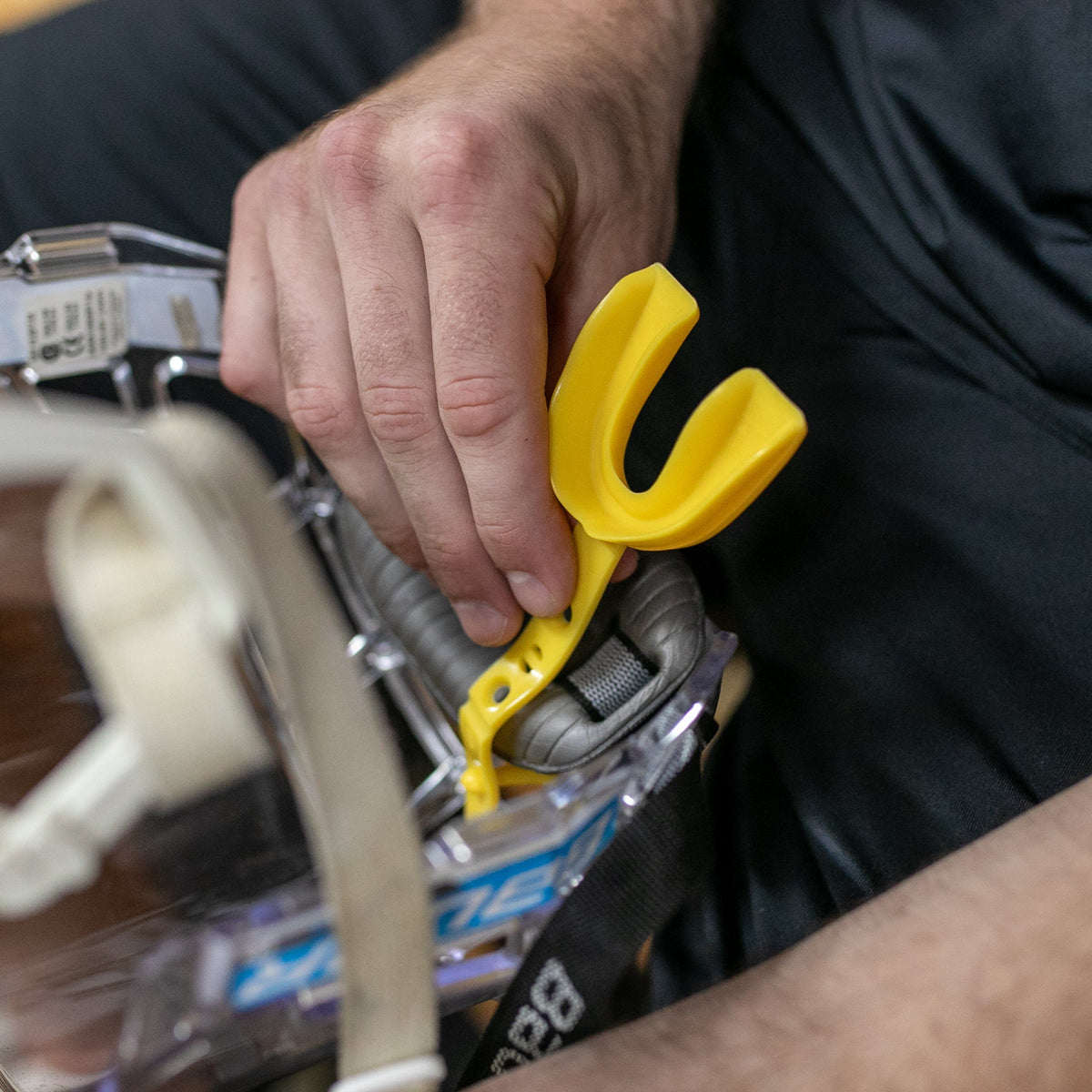 Yellow mouth guard being connected to a helmet 