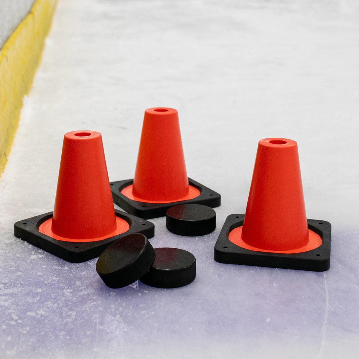 Red traffic cones on an ice rink with players in the background