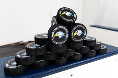Stack of hockey pucks with a logo on a blue surface