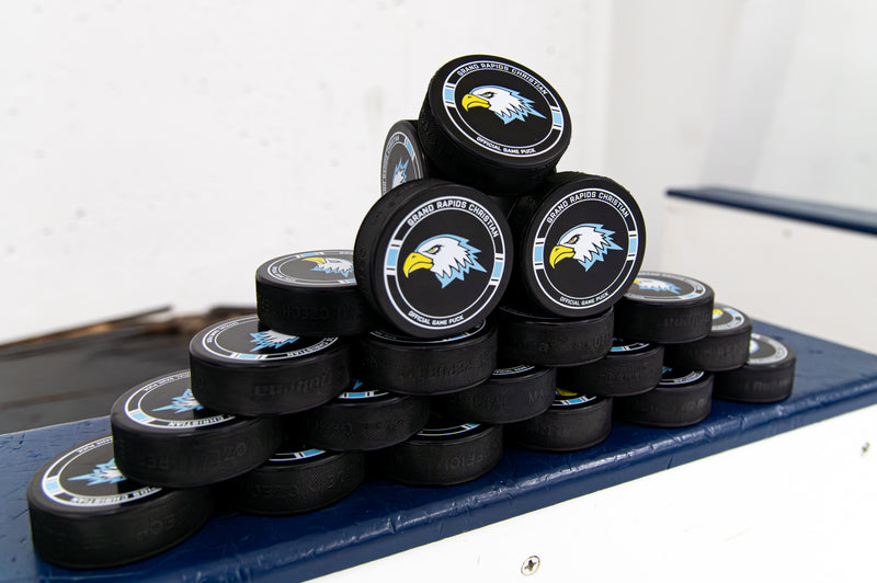 Stack of hockey pucks with a logo on a blue surface