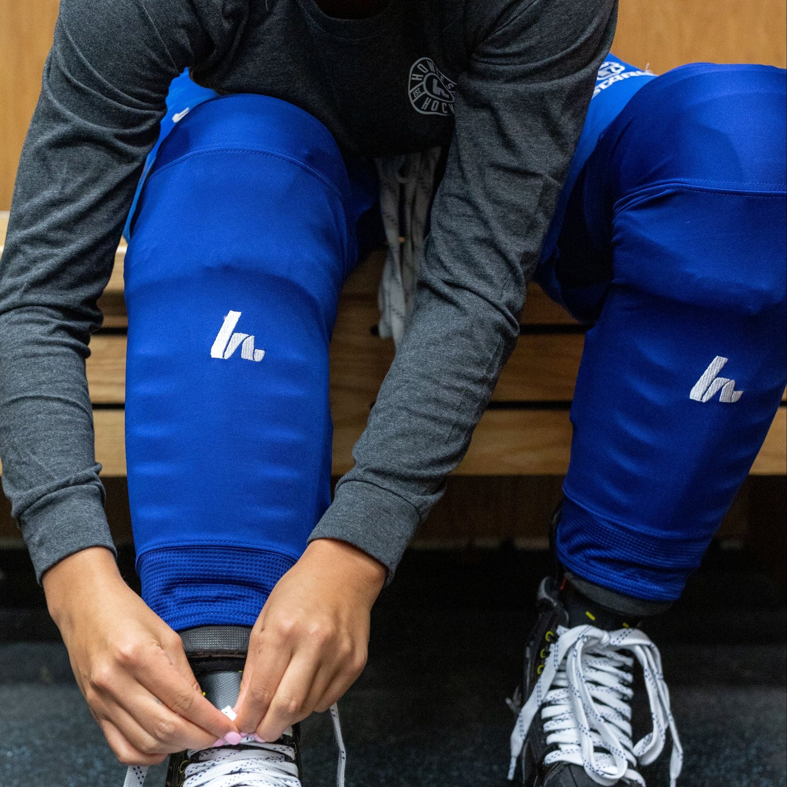 Person adjusting ice skates in a locker room setting