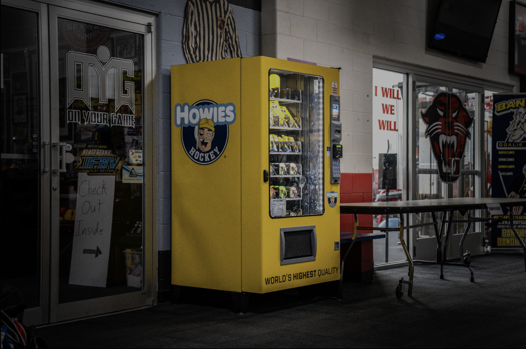 Yellow vending machine with 'Howies' branding in a store setting