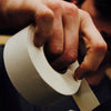 Close-up of a hand holding a roll of tape with a blurred background