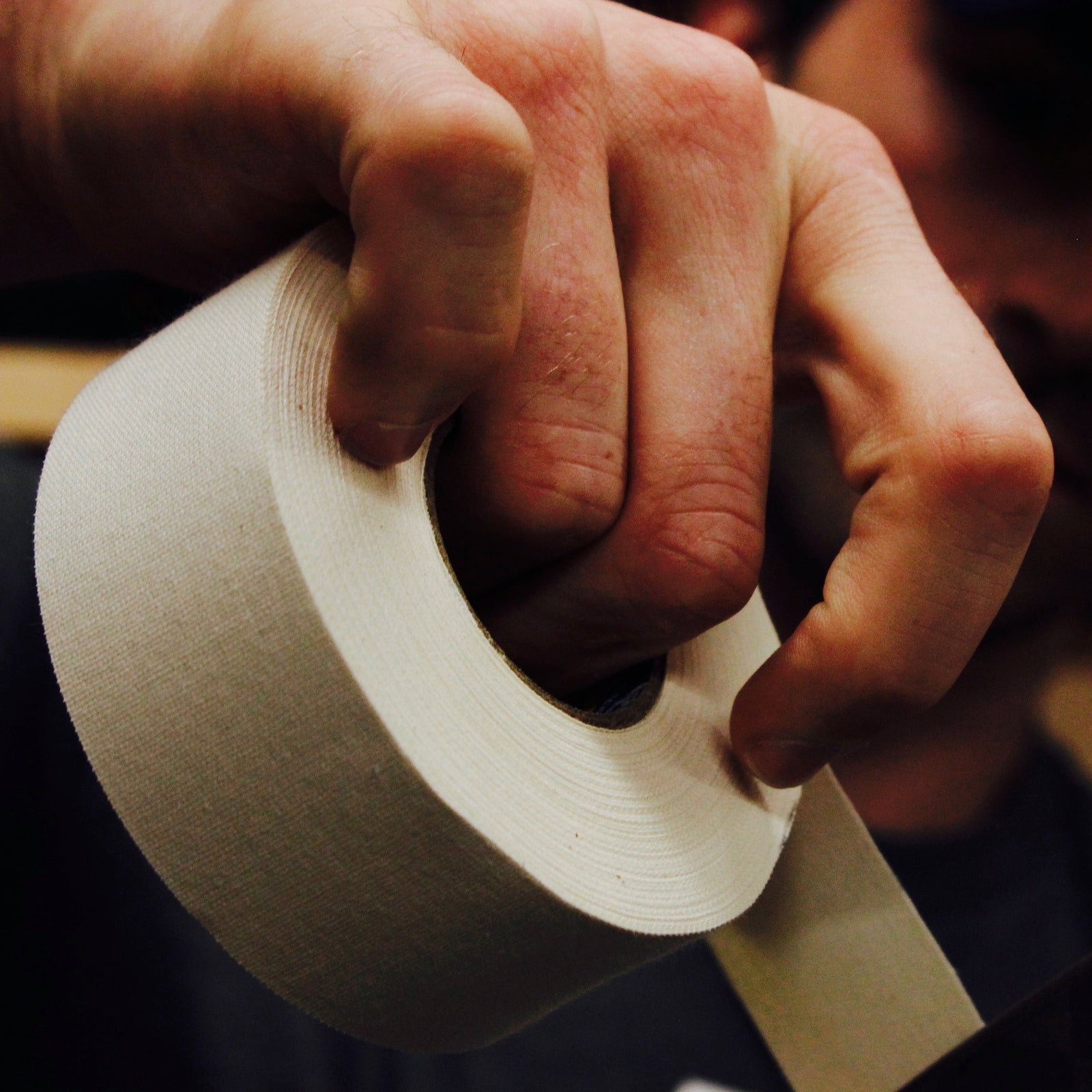 Close-up of a hand holding a roll of tape with a blurred background