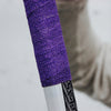 Close-up of a purple textured grip on a hockey stick with a blurred background.
