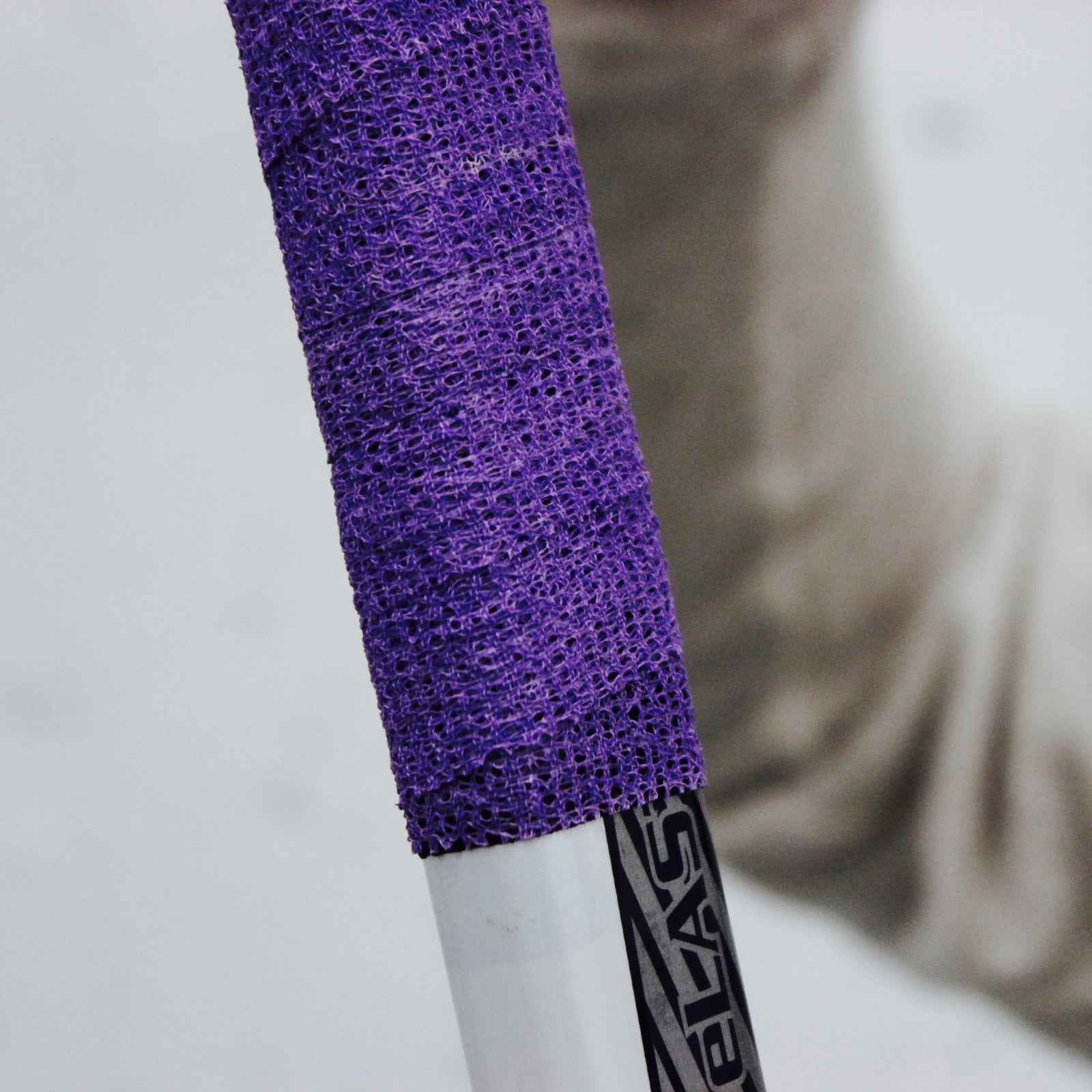 Close-up of a purple textured grip on a hockey stick with a blurred background.